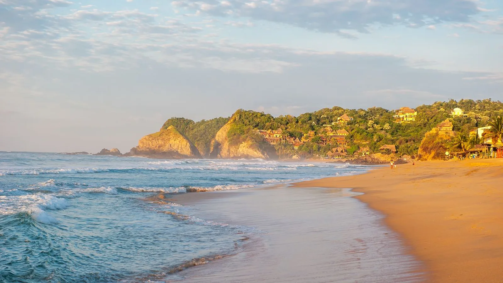 Playa Zipolite al atardecer con oleaje y palmeras en la costa de Oaxaca