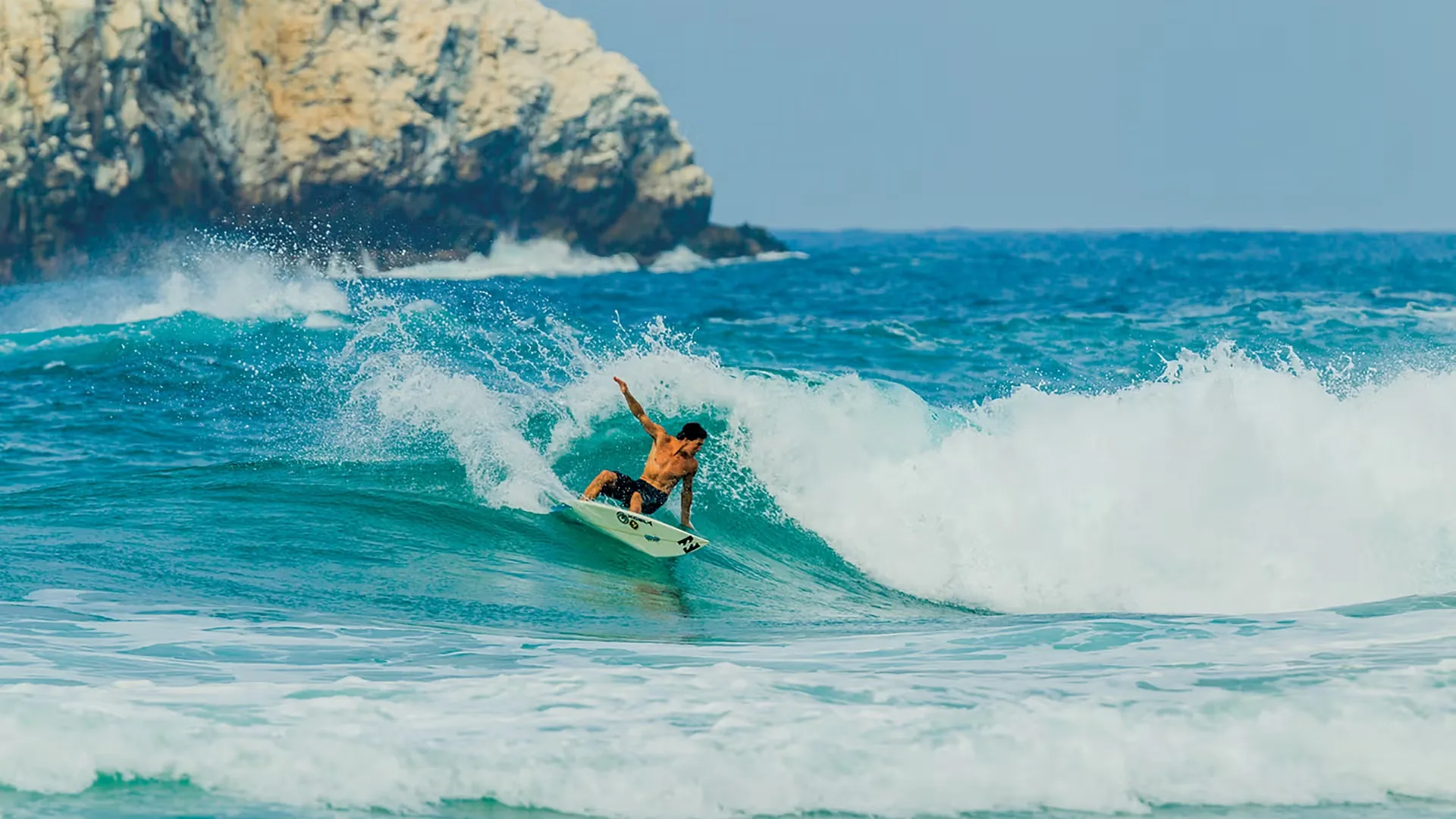 Surfista sobre una ola en la costa de Oaxaca cerca de Zipolite